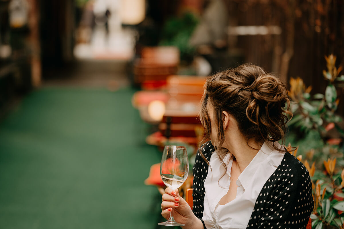 žena se skleničkou vína ve vinárně
