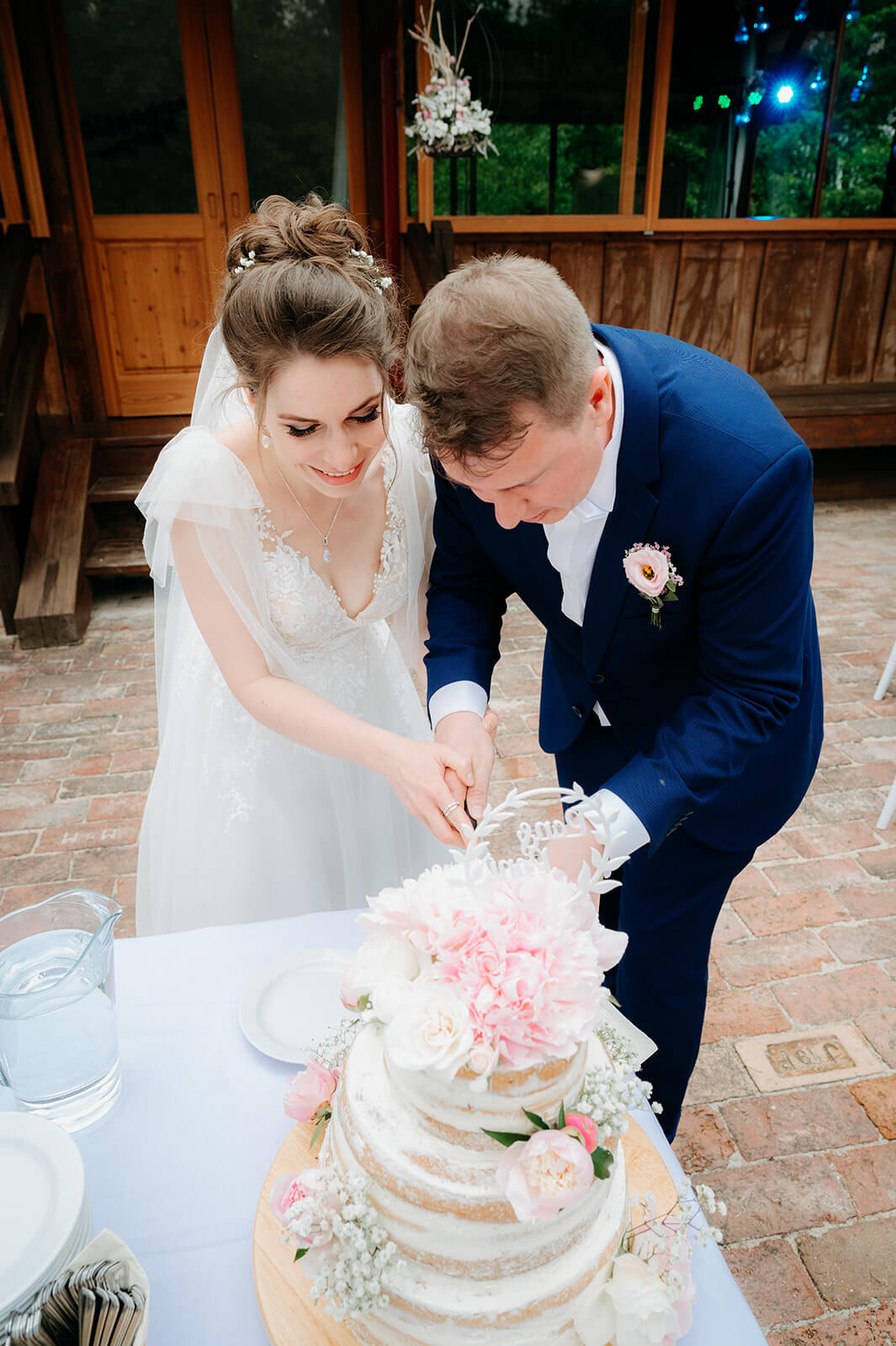 Nevěsta a ženich krájí svatební dort